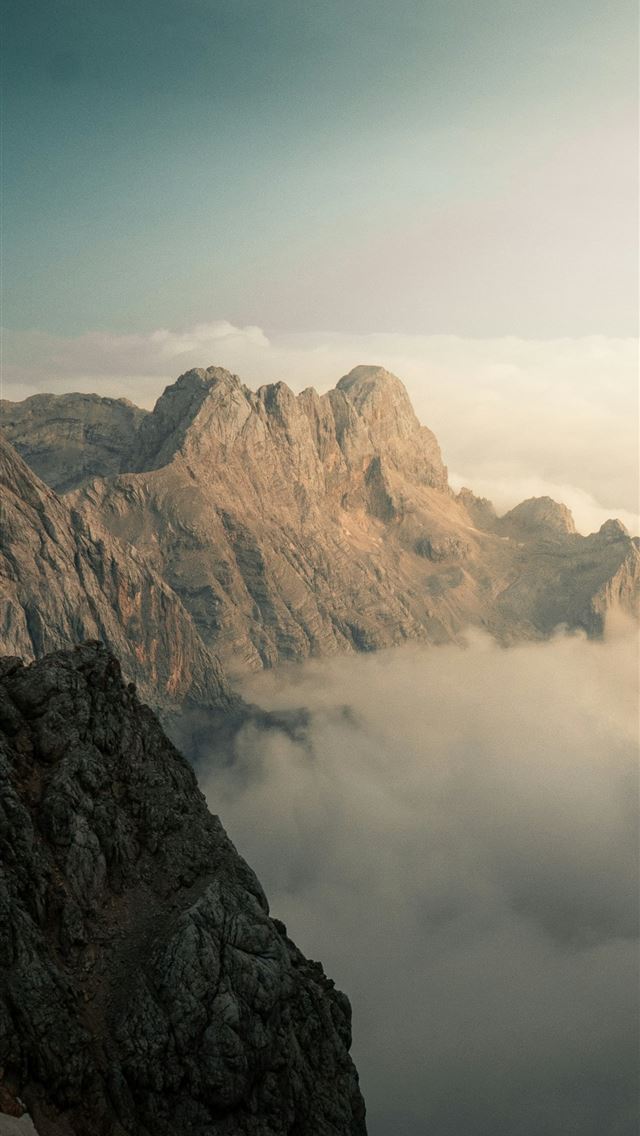 1290x2796 Rugged mountain peaks rising above a thick layer o... -  iPhone Wallpaper