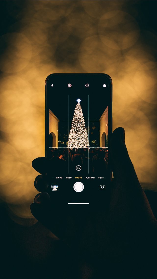 640x1136 person taking photo of Christmas tree - holiday iPhone Wallpaper