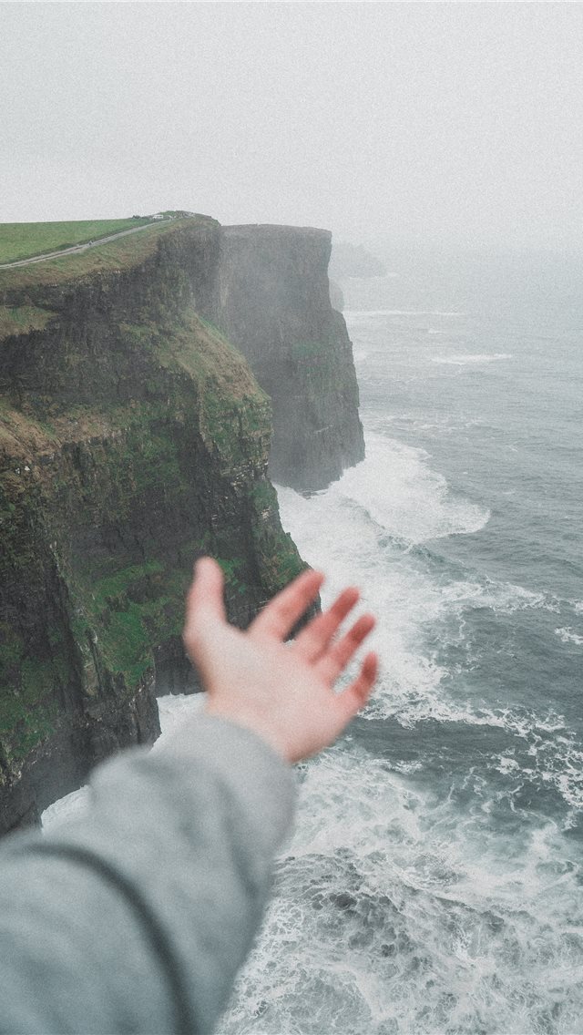 640x1136 person standing on the cliff near the ocean - ireland iPhone Wallpaper