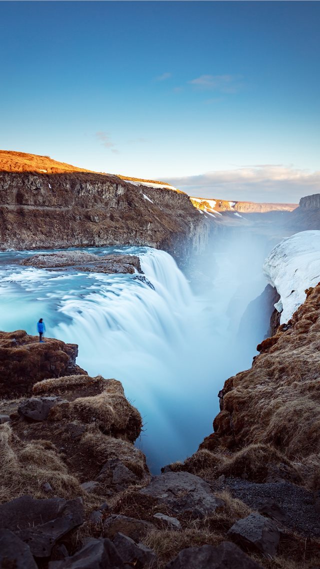 640x1136 person standing on cliff near large waterfalls und... - iceland iPhone Wallpaper