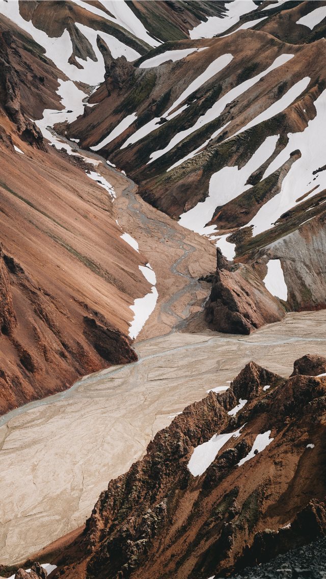 brown mountain covered by melting snow iPhone wallpaper 