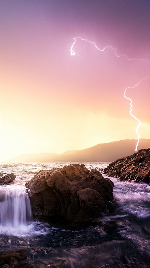 rock formation near sea under thunder light iPhone wallpaper 