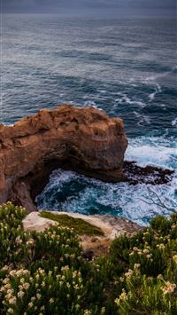 ocean wave crashing on rocky island during day wallpaper