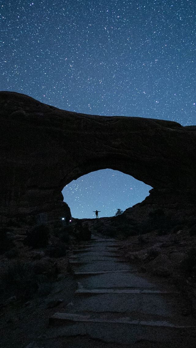 person standing near mountain during nighttime iPhone wallpaper 