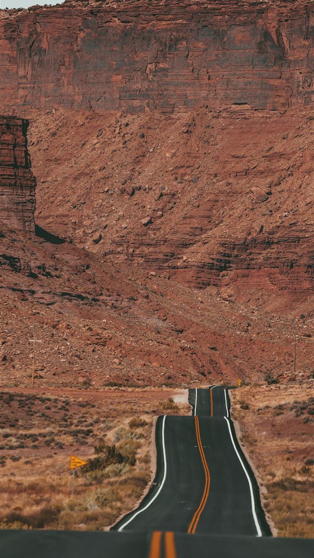 white car on road near brown rock formation during... iPhone wallpaper 