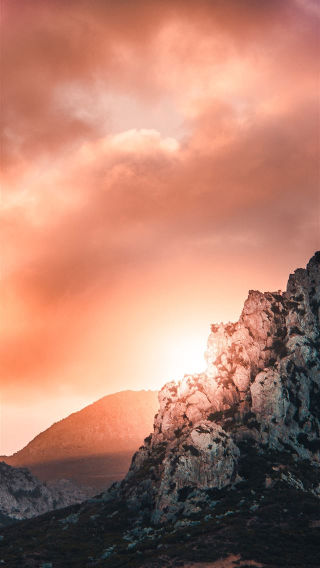 black and gray hill under cloudy sky during sunset iPhone wallpaper 