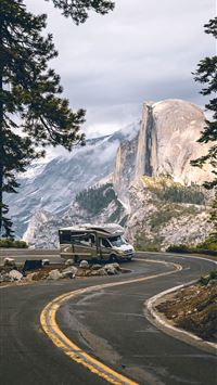black suv on road near trees and snow covered moun... wallpaper
