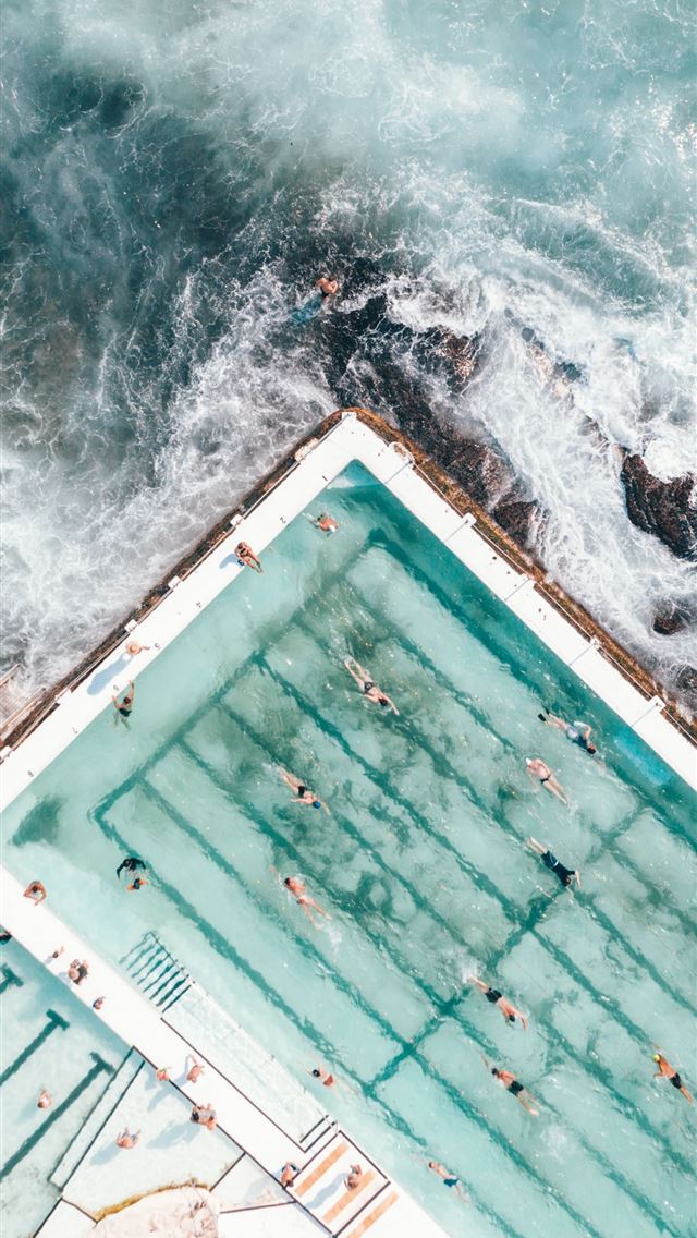 pool with people swimming nearby seashore iPhone wallpaper 