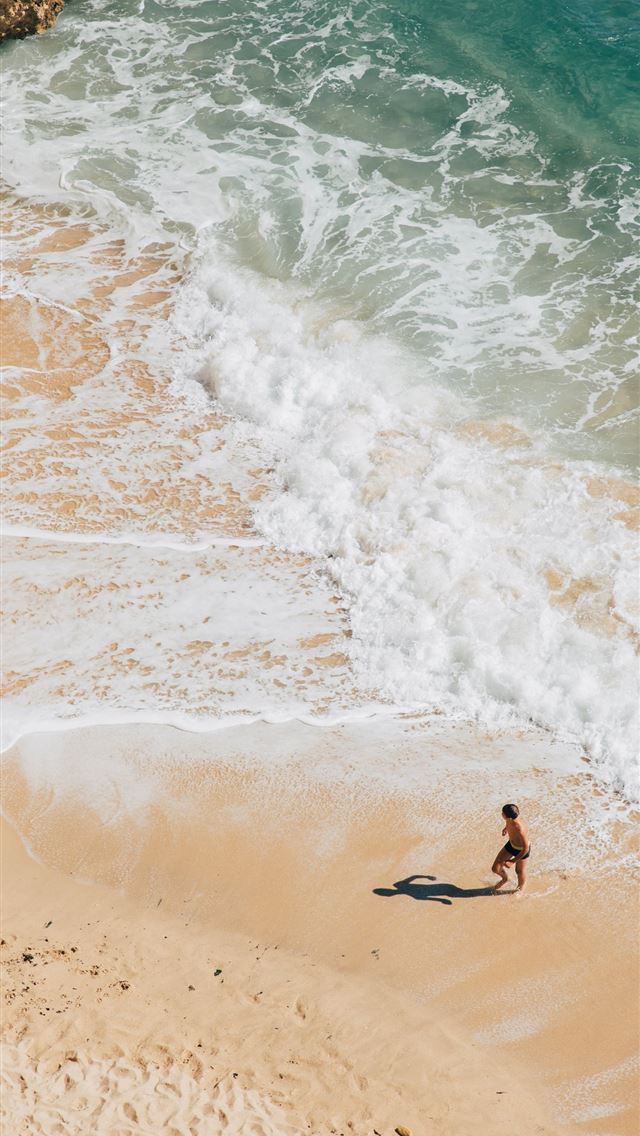 woman walking on seashore iPhone wallpaper 