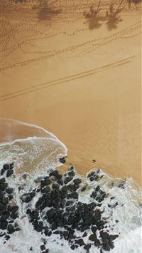 water hitting rocks on shore near trees during day... wallpaper