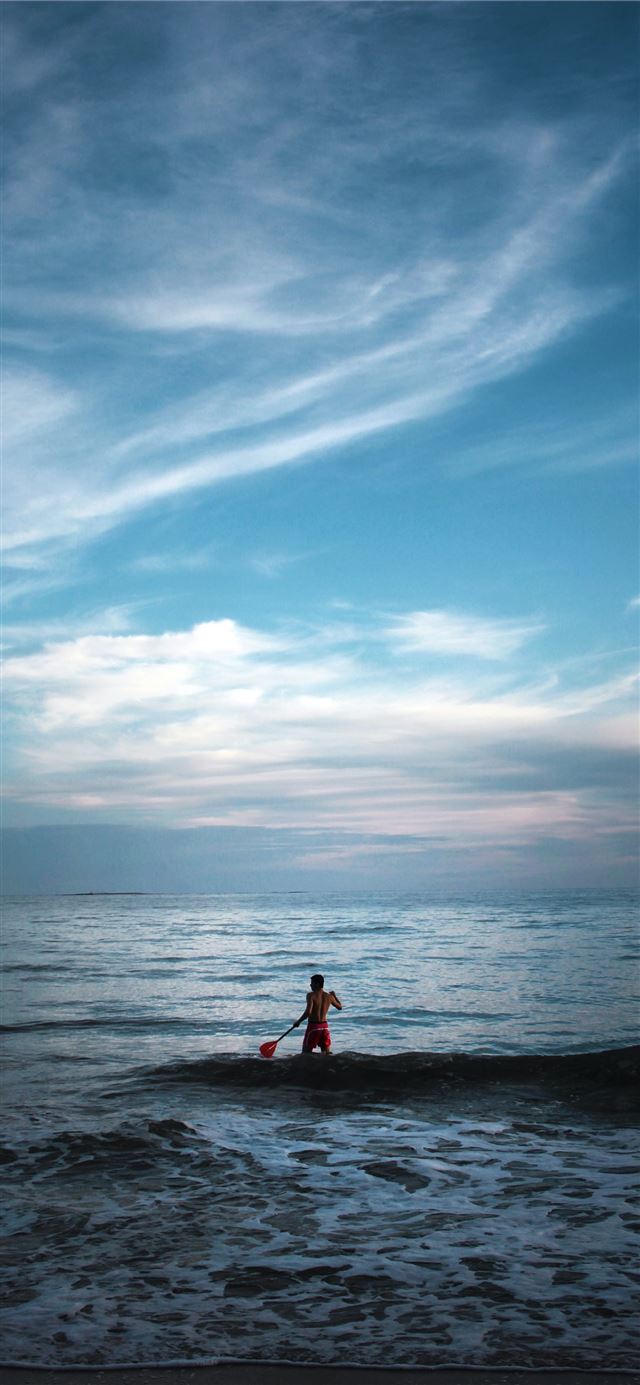 1125x2436 man standing on body of water holding paddle -  iPhone X Wallpaper