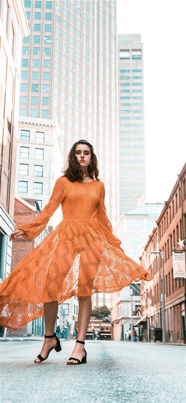 1125x2436 woman in orange long sleeved dress between buildin... - orange iPhone X Wallpaper