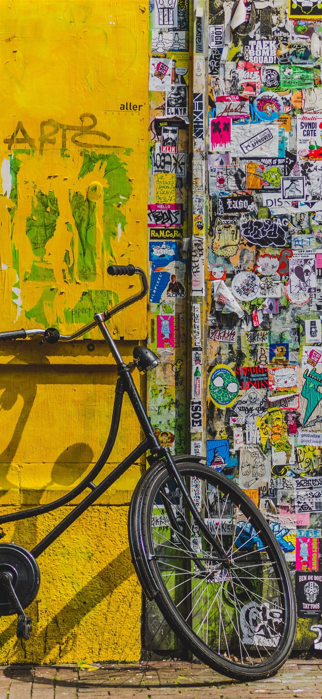 bike parked beside wall full of stickers iPhone X wallpaper 