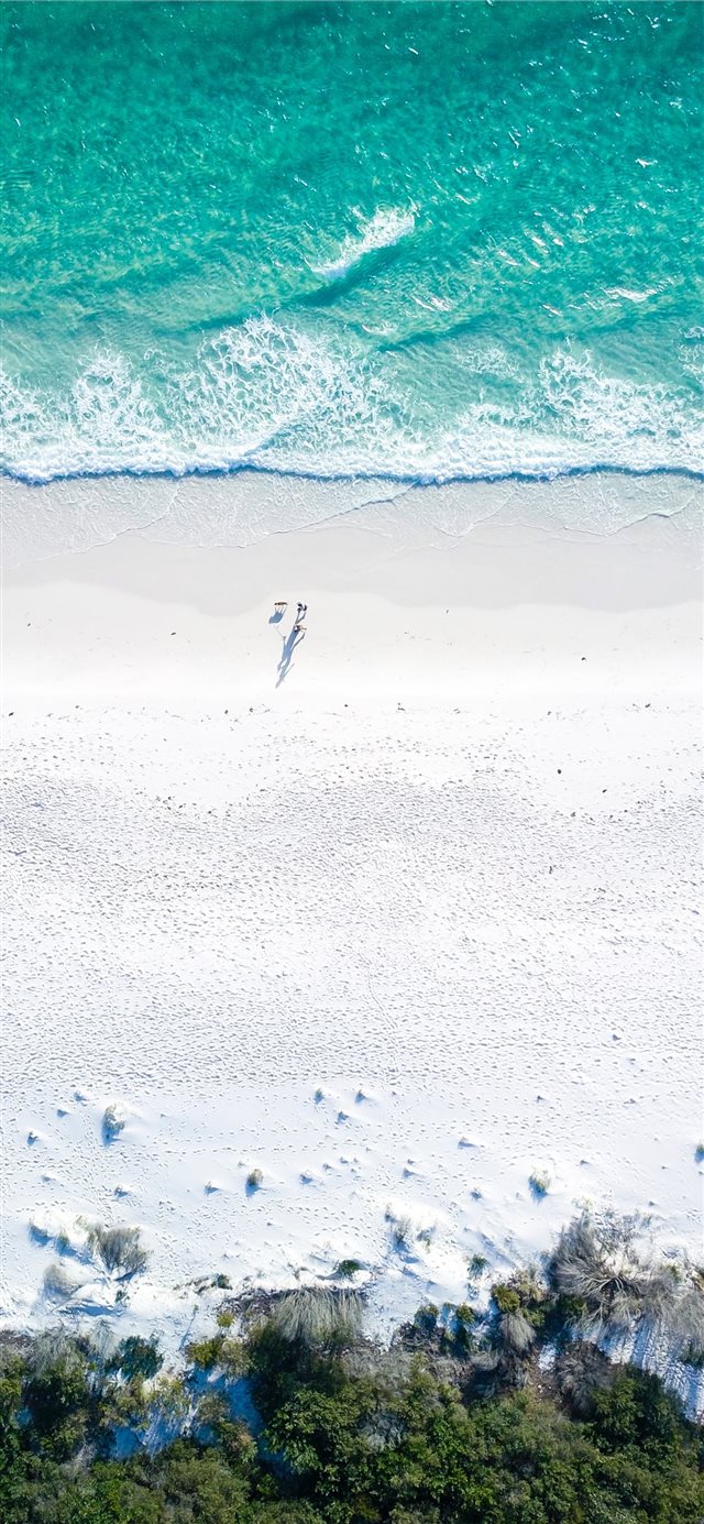 1125x2436 two people on beach during daytime - water iPhone X Wallpaper