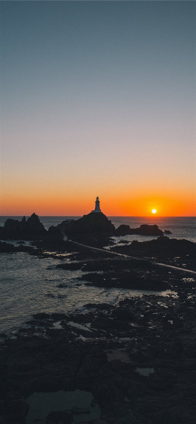 1125x2436 man standing on rock formation during golden hour - light iPhone X Wallpaper