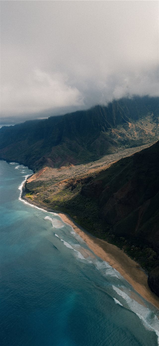 1125x2436 green mountain near body of water under grey sky - landscape iPhone X Wallpaper