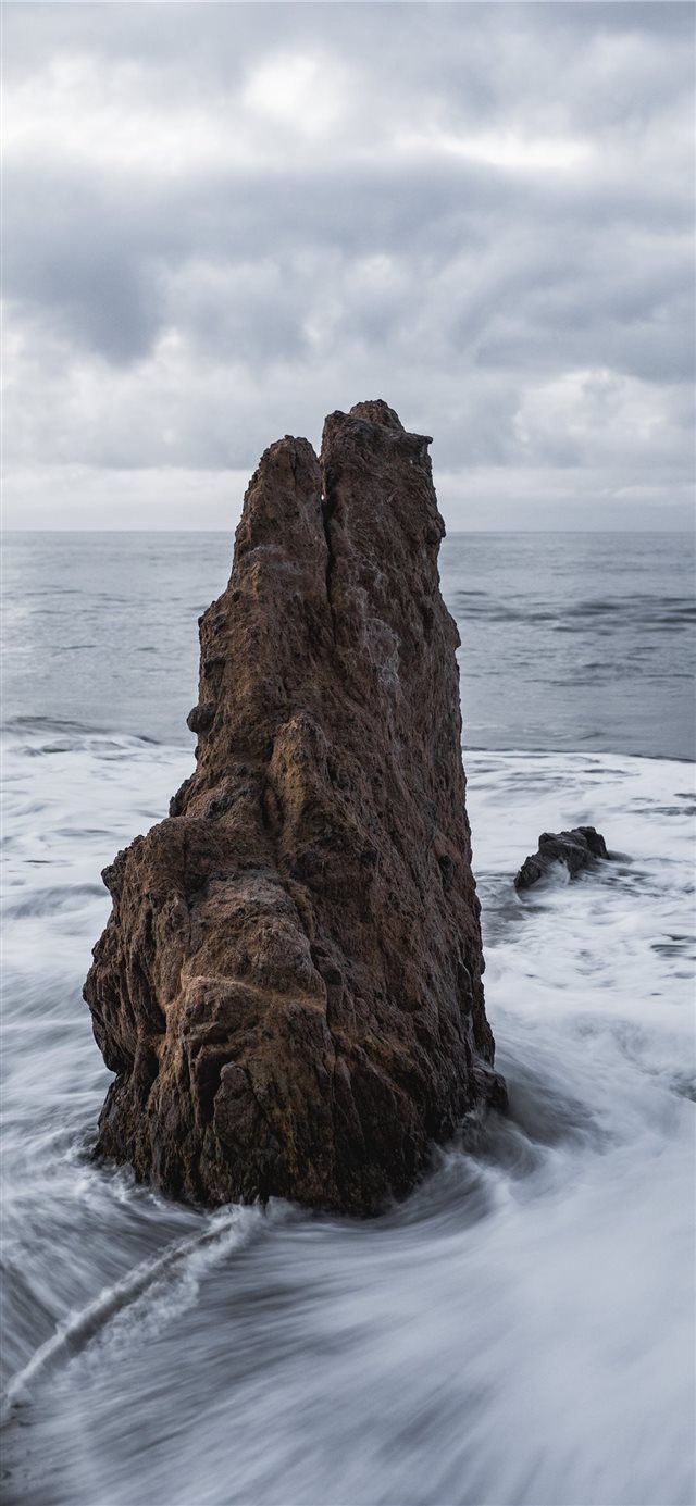 1125x2436 brown rock on body of water across horizon - grey iPhone X Wallpaper
