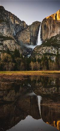 reflection of rock mountain and waterfalls on wate... wallpaper