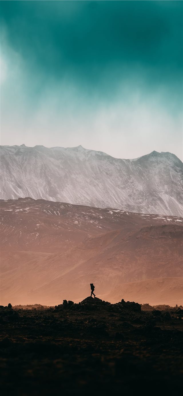 1125x2436 person standing on rock near snow covered mountain... - landscape iPhone X Wallpaper