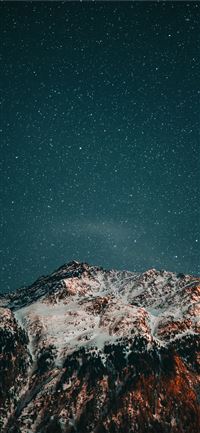 snow covered mountain under starry night wallpaper