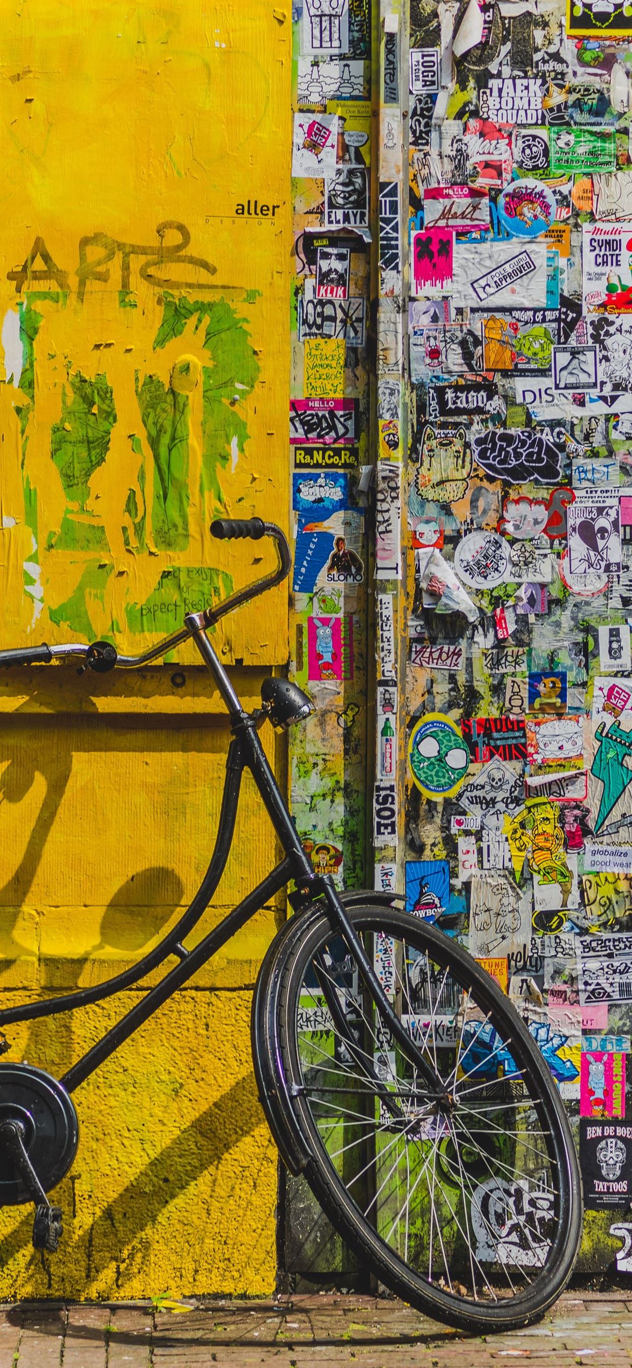 bike parked beside wall full of stickers iPhone X Wallpapers Free Download