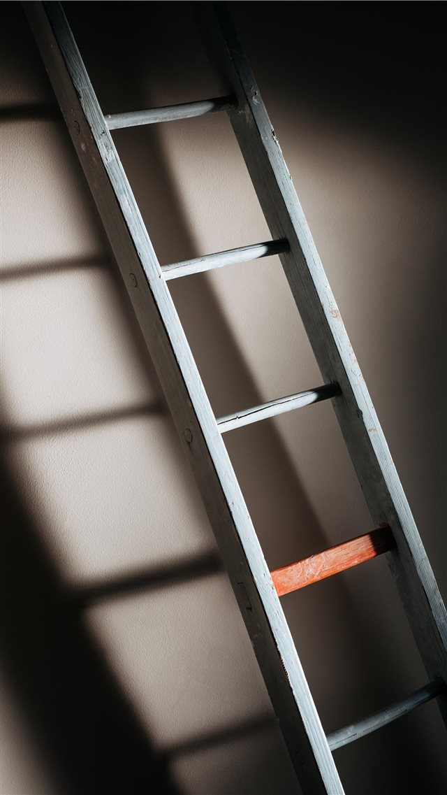 An old wooden ladder casting soft shadows on wall iPhone 8 wallpaper 