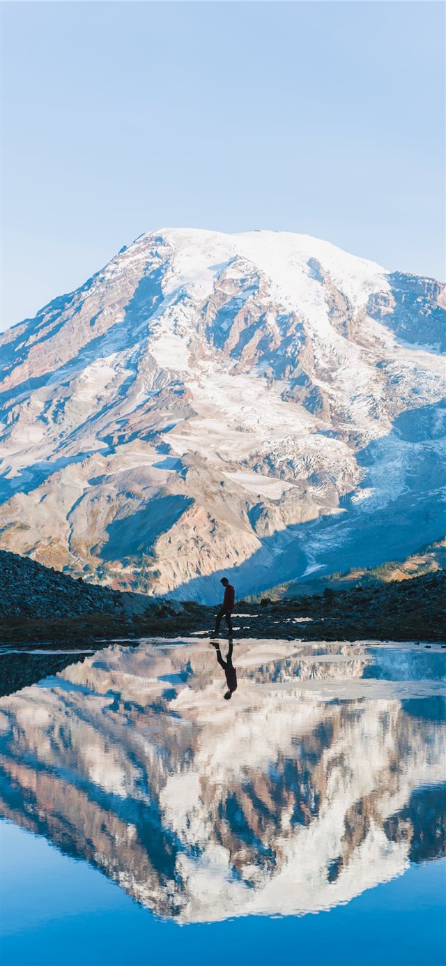 man walking near glacier mountain during day iPhone 11 wallpaper 