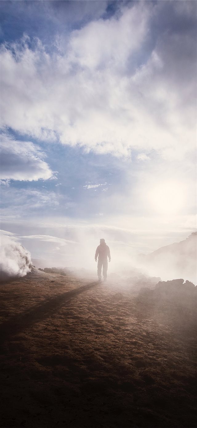 person standing near the edge of a mountain near c... iPhone X wallpaper 