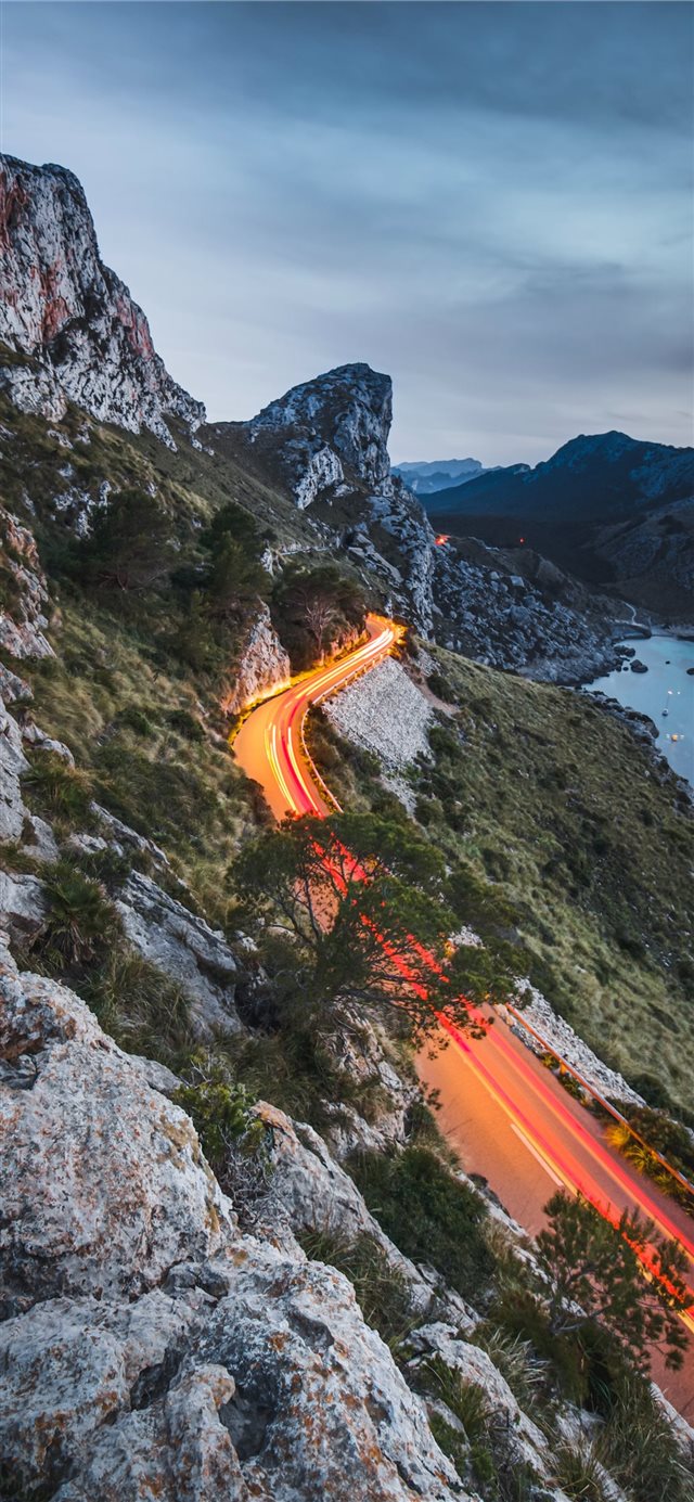 road beside a cliff near body of water during dayt... iPhone 11 wallpaper 