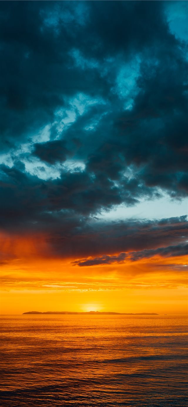 green and black clouds partly covering orange sky ... iPhone X wallpaper 