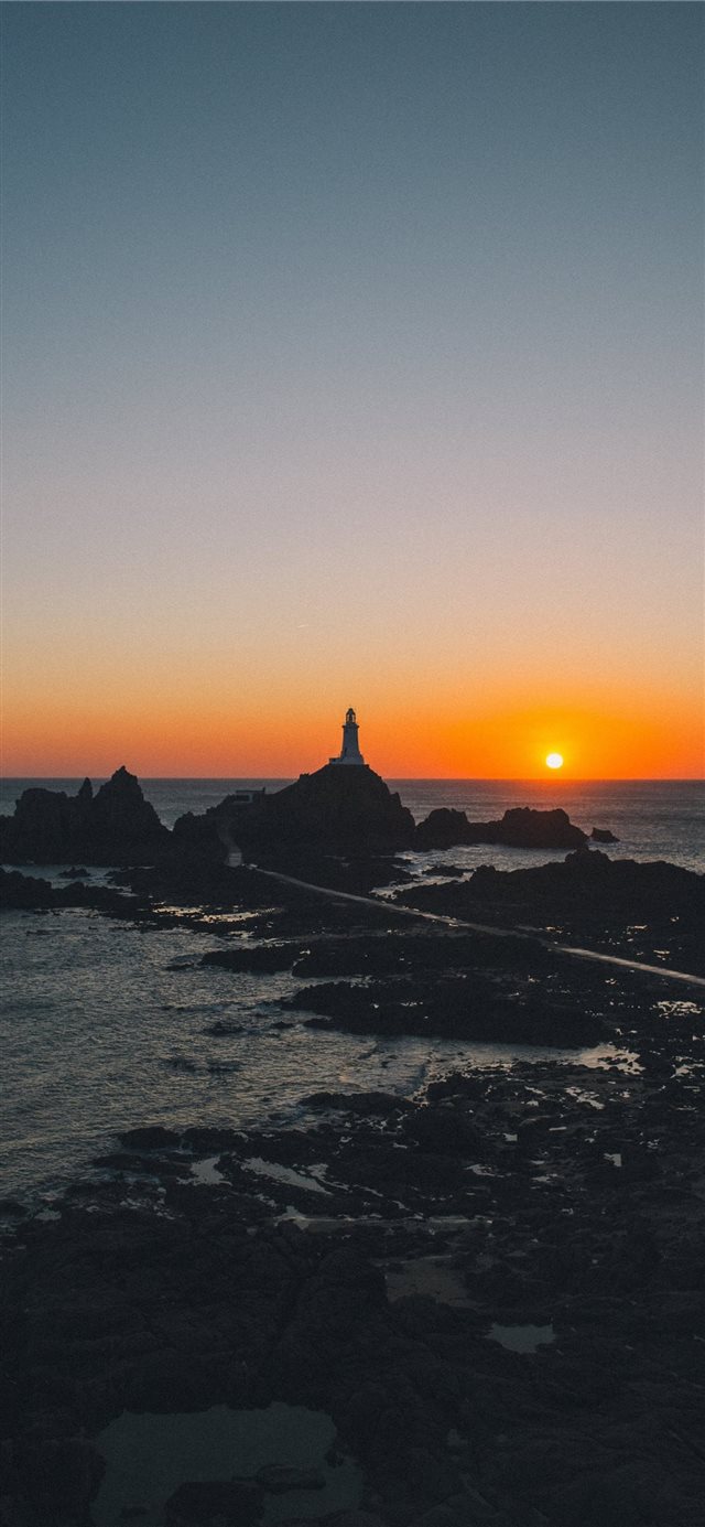 man standing on rock formation during golden hour iPhone X wallpaper 