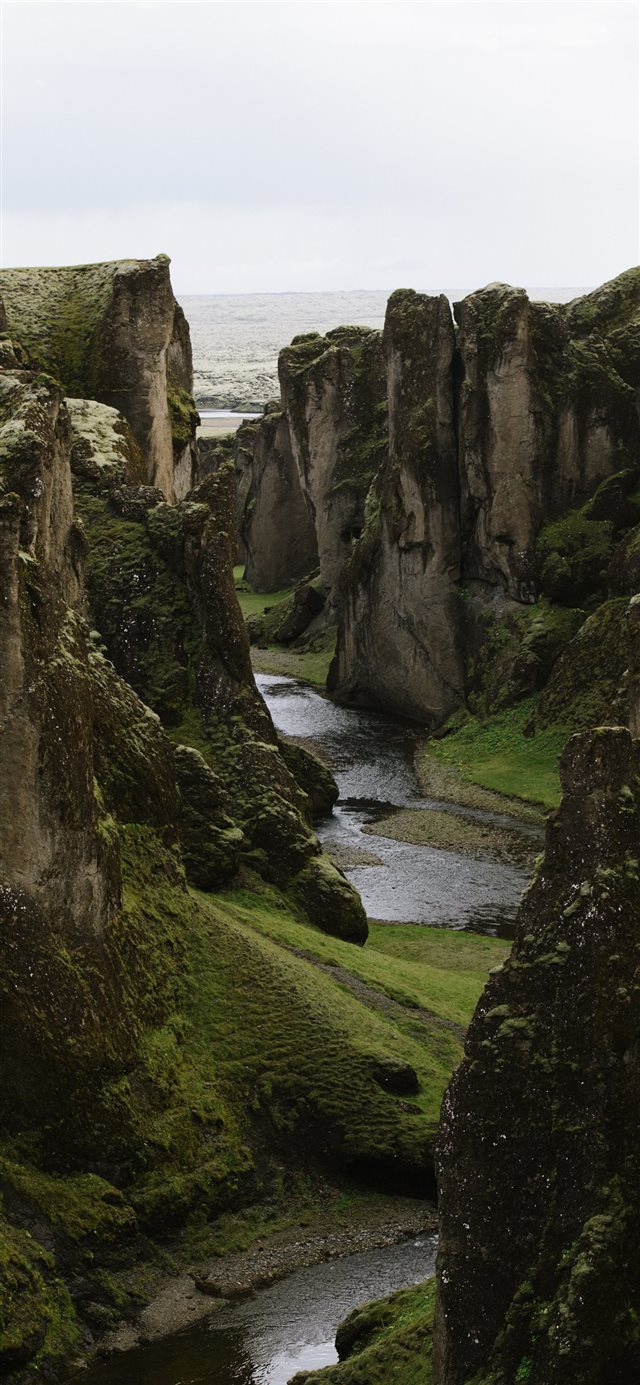 river in deep gorge between rock faced hills iPhone X wallpaper 