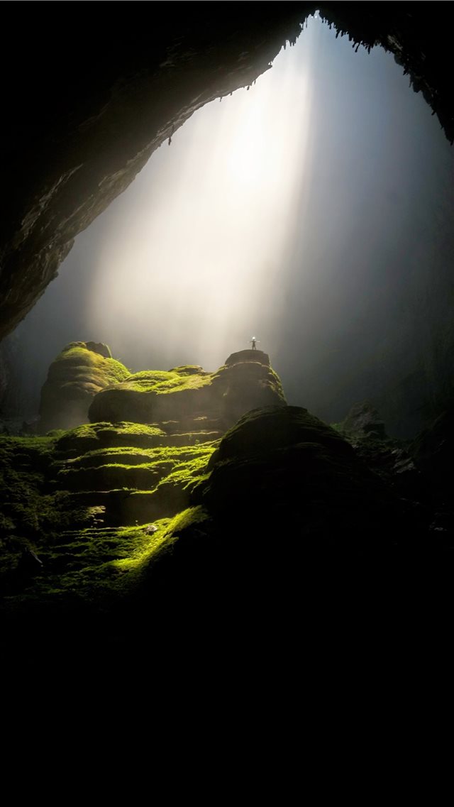 person on top of rock formation inside cave iPhone 8 wallpaper 