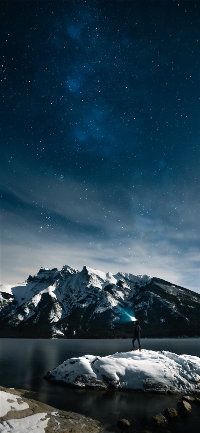 person standing on rock at night iPhone 11 wallpaper 