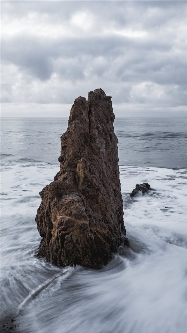 brown rock on body of water across horizon iPhone 8 wallpaper 