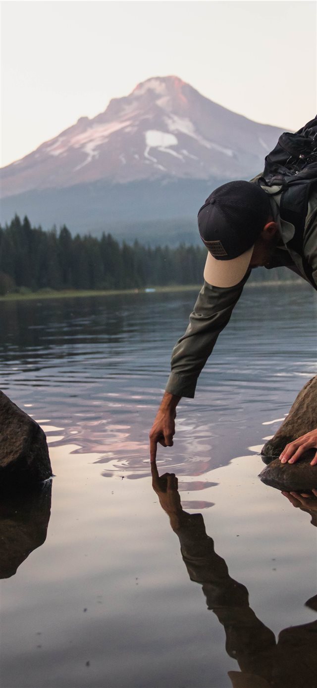 man putting finger on water viewing mountain iPhone X wallpaper 