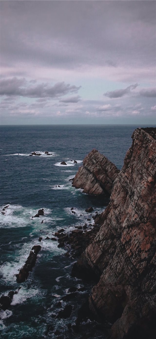 rock formation near the sea during daytime iPhone X wallpaper 