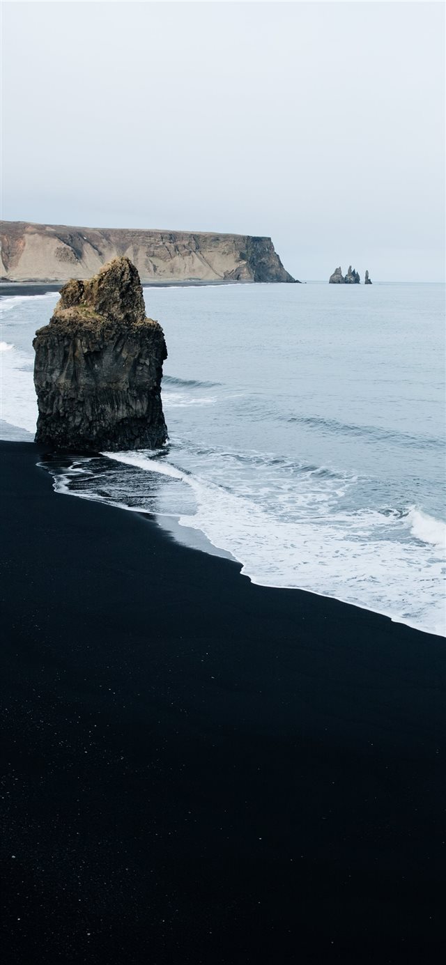 brown monolith rock on seashore iPhone 11 wallpaper 