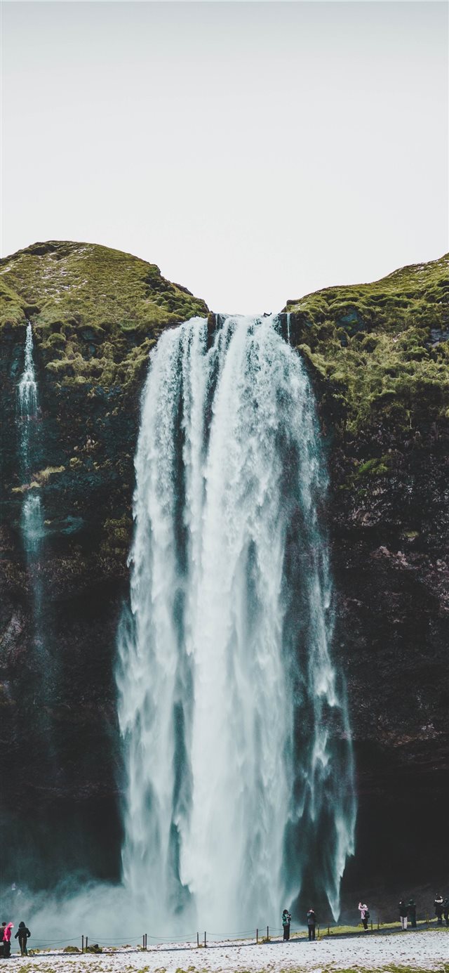 group of people standing near waterfalls iPhone X wallpaper 