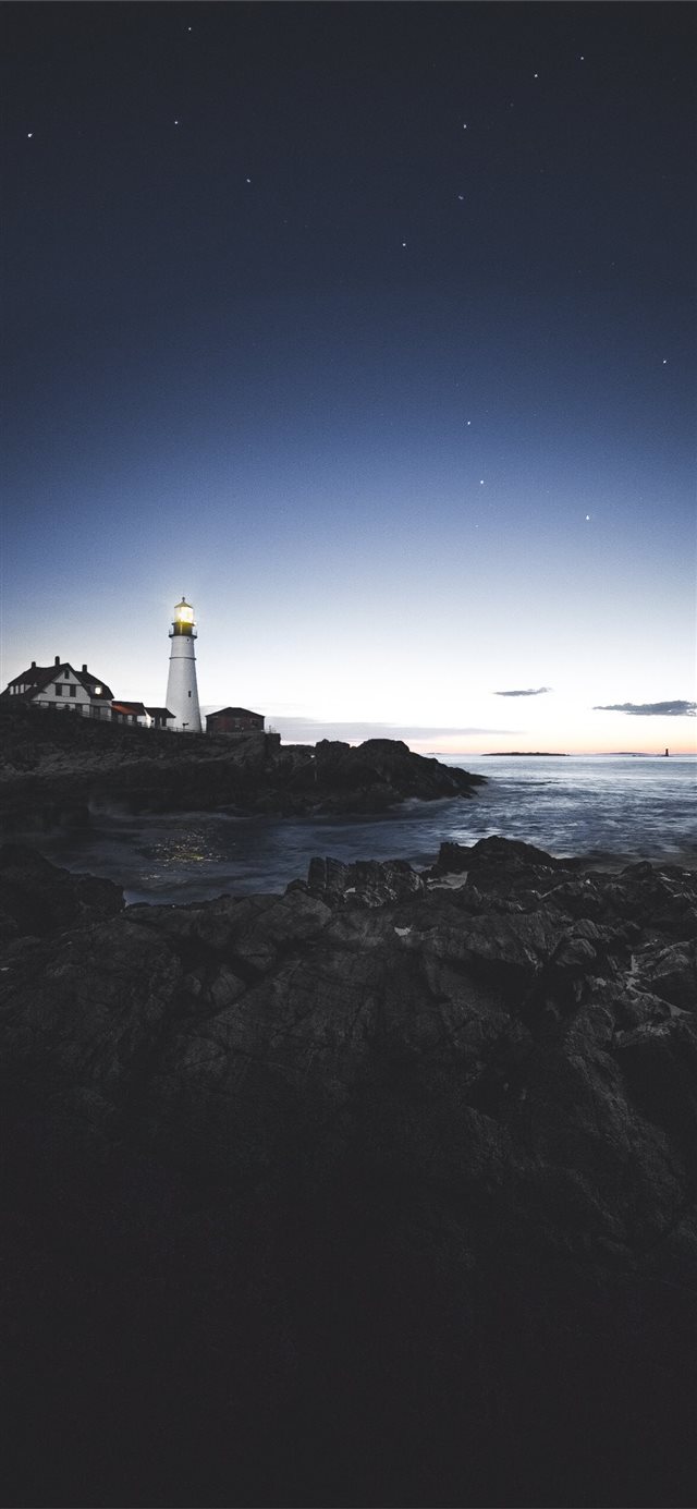 lighthouse beside house near the edge of stone isl... iPhone X wallpaper 