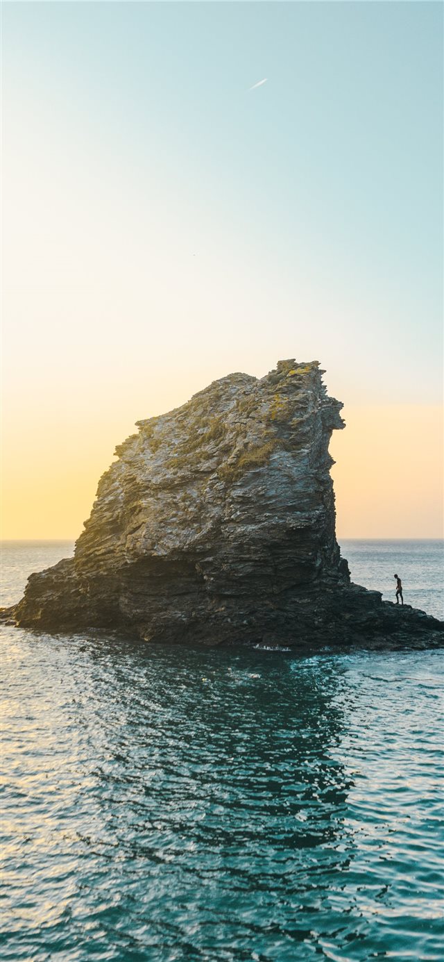 two people standing on rock formation surrounded b... iPhone 11 wallpaper 