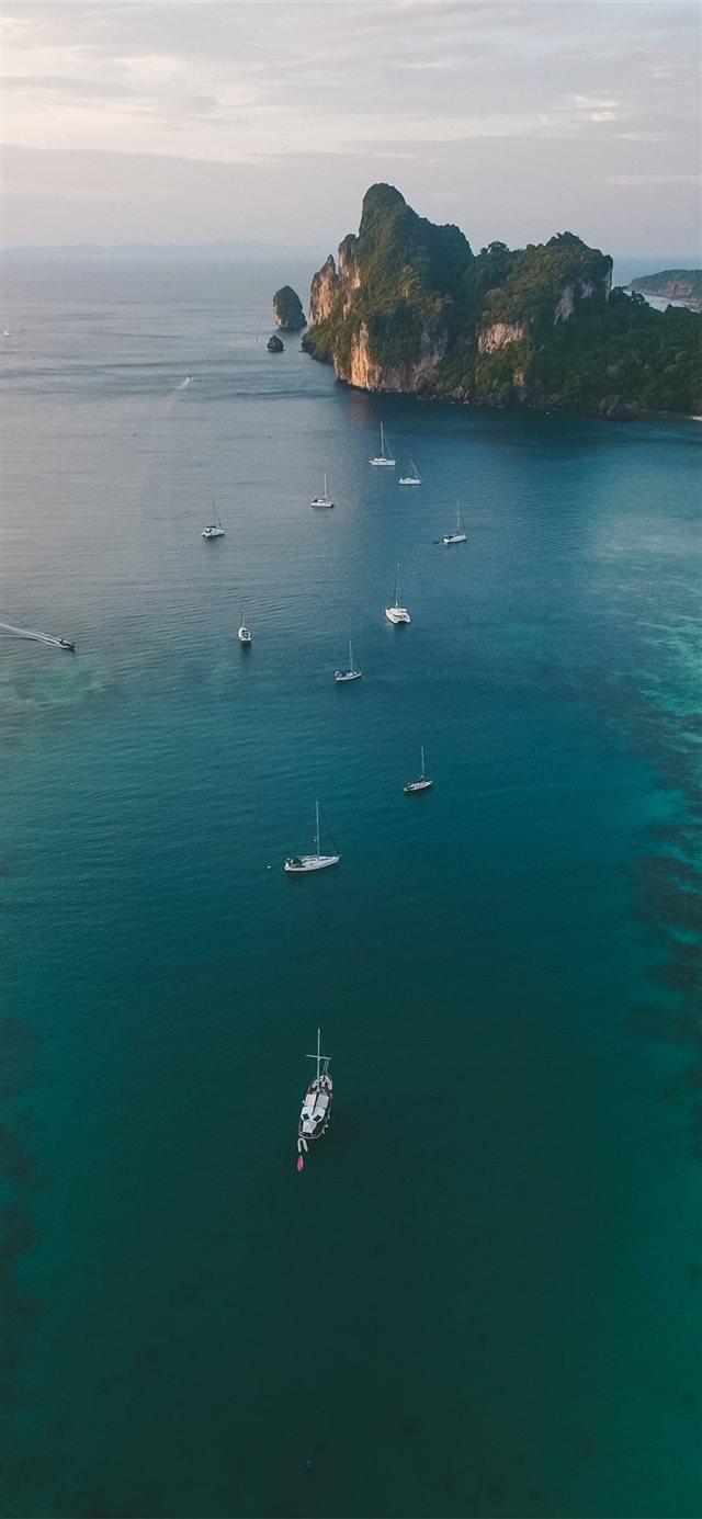 white boats on ocean water under gray sky iPhone X wallpaper 