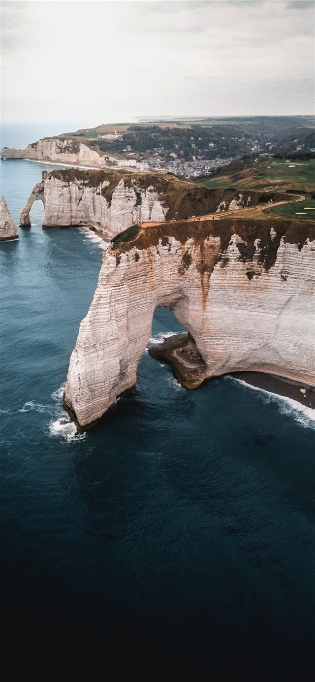 brown and green cliff and body of water iPhone X wallpaper 