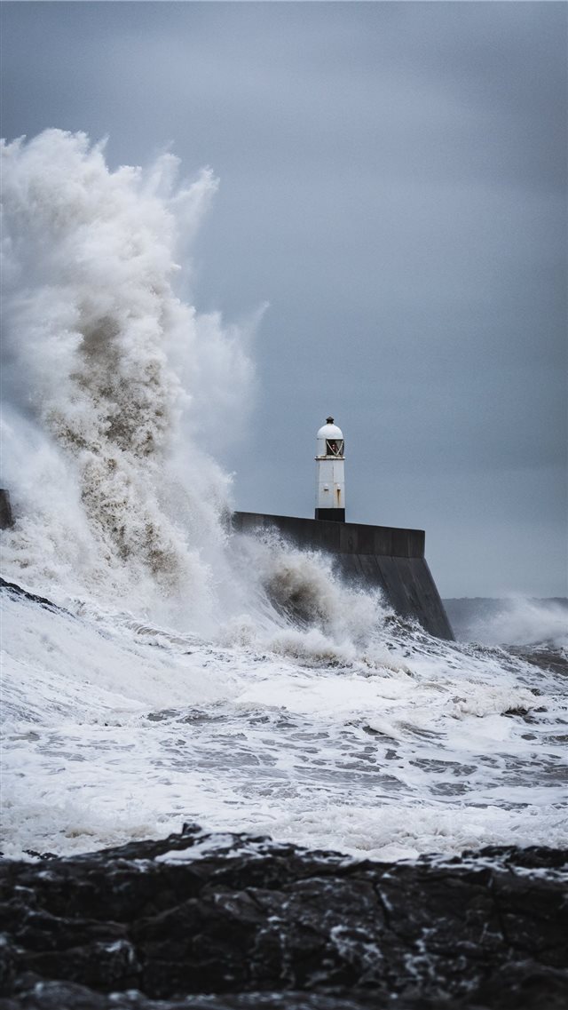 big waves crashing on lighthouse during daytime iPhone 8 wallpaper 
