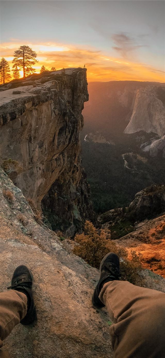 person pair of shoes and sitting on edge of mounta... iPhone 11 wallpaper 
