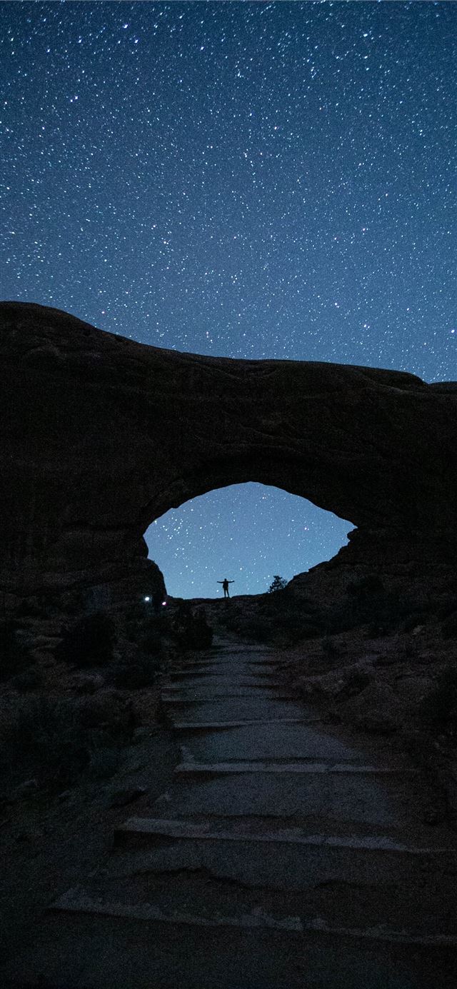 person standing near mountain during nighttime iPhone 11 wallpaper 