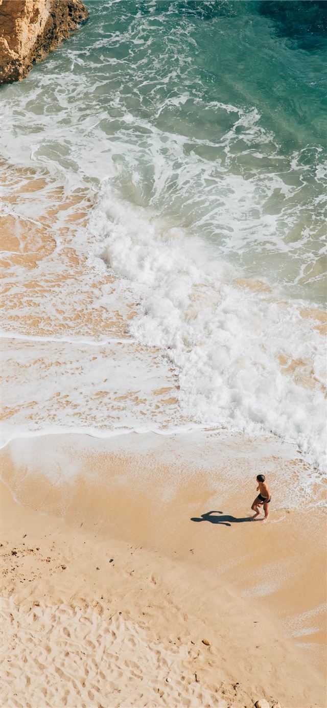 woman walking on seashore iPhone X wallpaper 