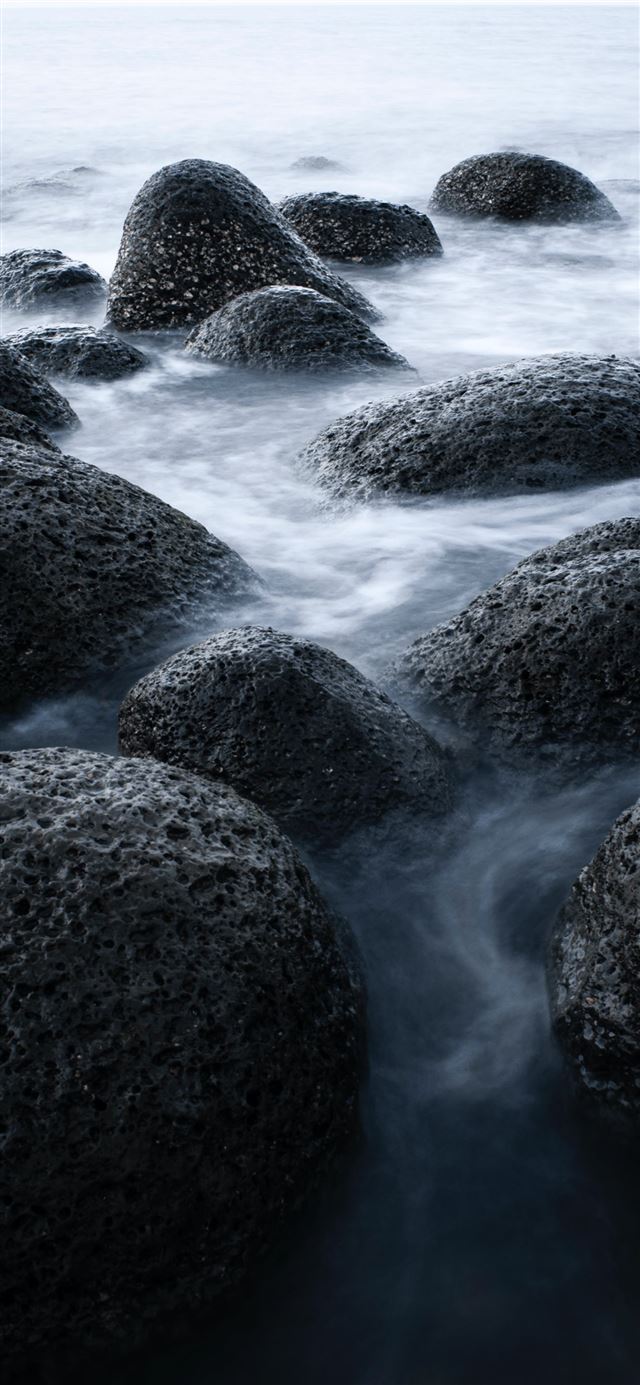 black rock formation on body of water during dayti... iPhone 11 wallpaper 