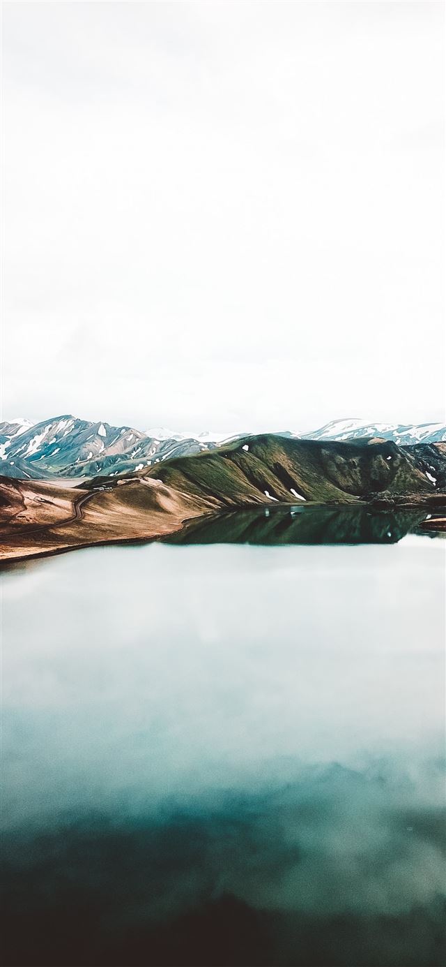 body of water across brown mountain iPhone X wallpaper 