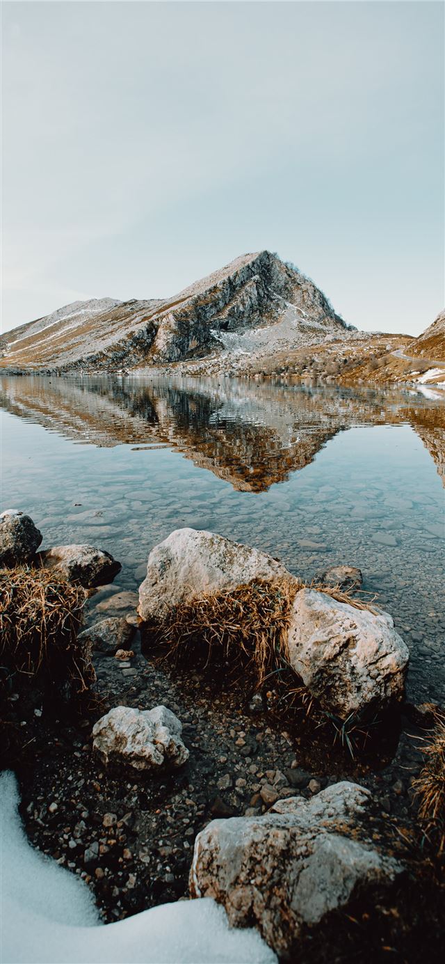 brown rocky mountain beside lake under blue sky du... iPhone 11 wallpaper 